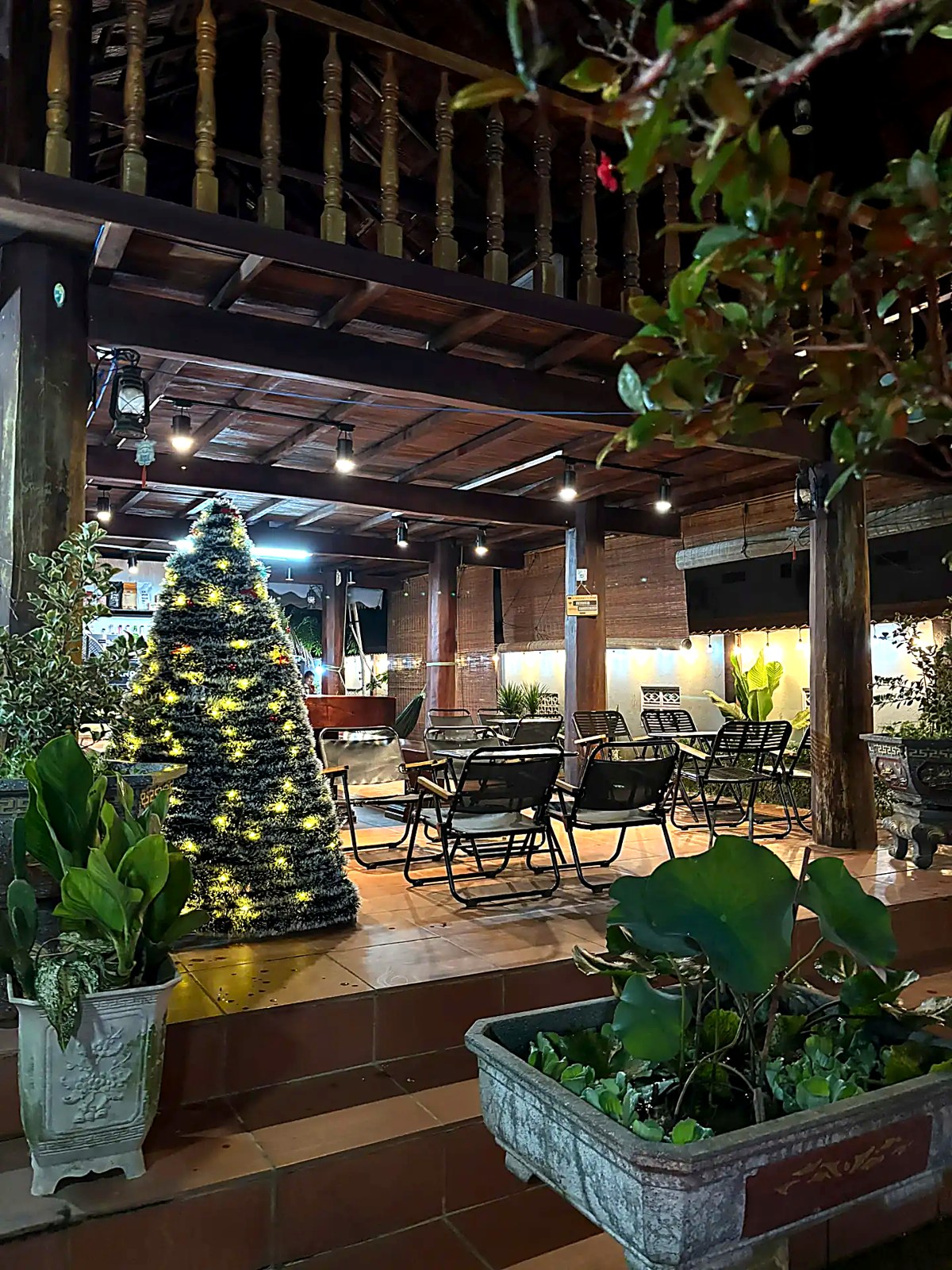 Sân vườn nhà gỗ buổi tối với đèn vàng ấm và cây xanh