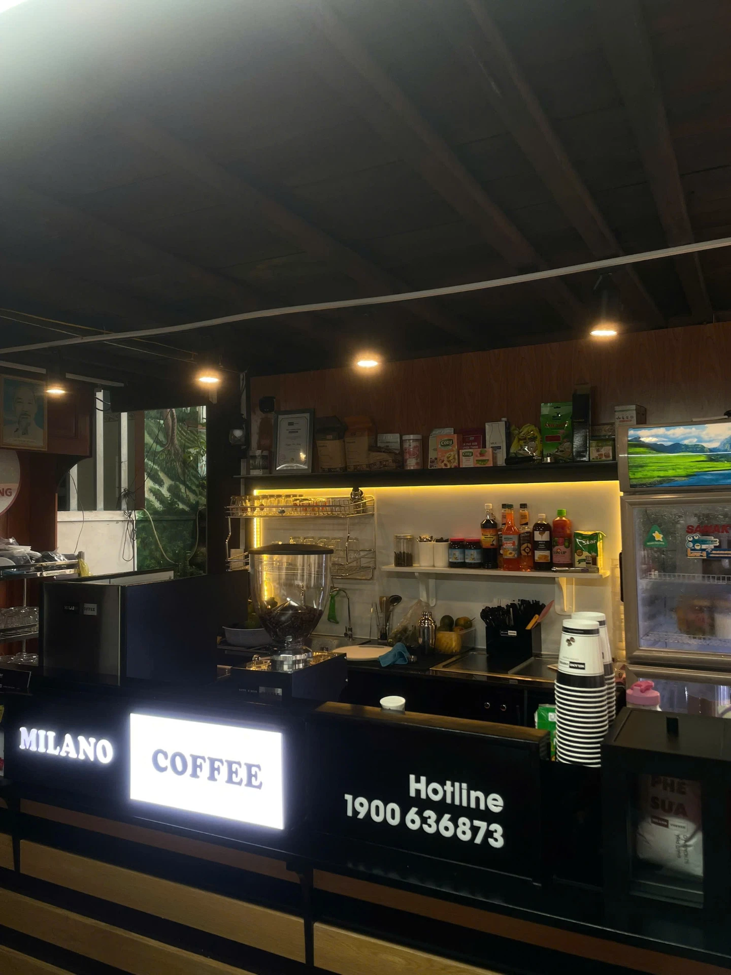 Quầy pha chế Milano Coffee với máy espresso và bảng hiệu sáng đèn